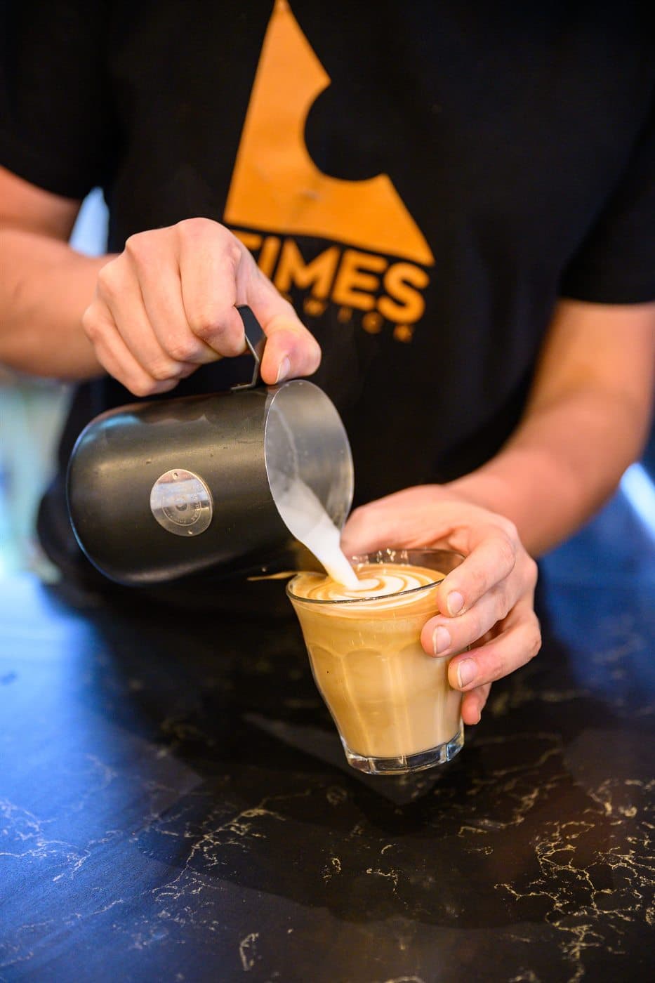 A Times Cafe barista pouring latte art